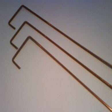 Three metal rods with bent ends arranged parallel to each other on a light surface.
