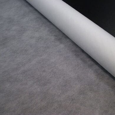 A roll of thin, semi-transparent white fabric is partially unrolled on a flat surface, showing its soft, even texture.